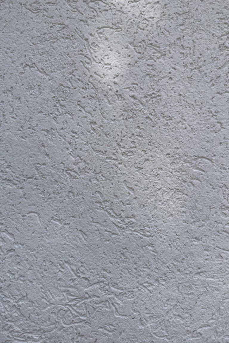 Detailed view of a white textured wall surface in natural light.