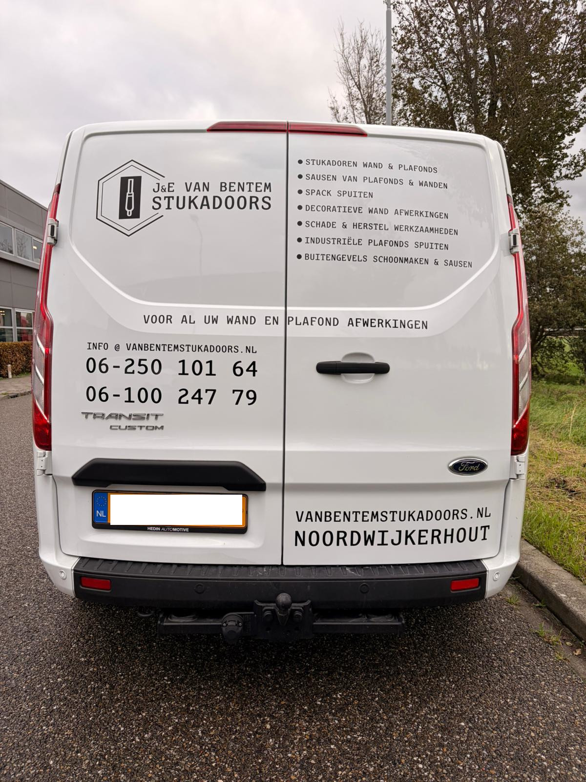 Achterkant werkbus met info over J en E stukadoors en het mobiele nummer 0625010164