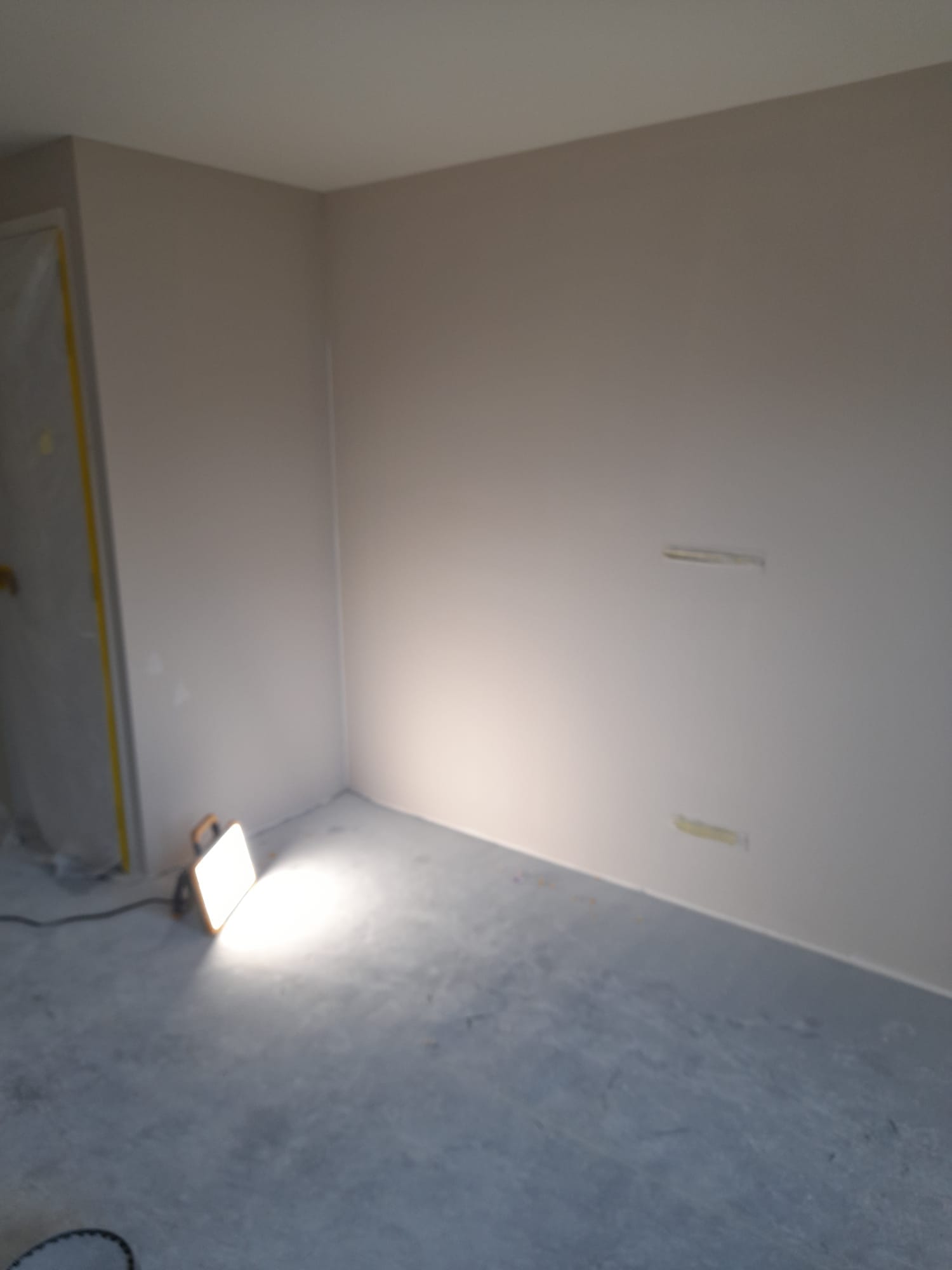 Sauswerk en spuitwerk woning in Lisse 4 Woning in Lisse met gespoten plafond en twee kleuren wanden, verlicht door een bouwlamp.