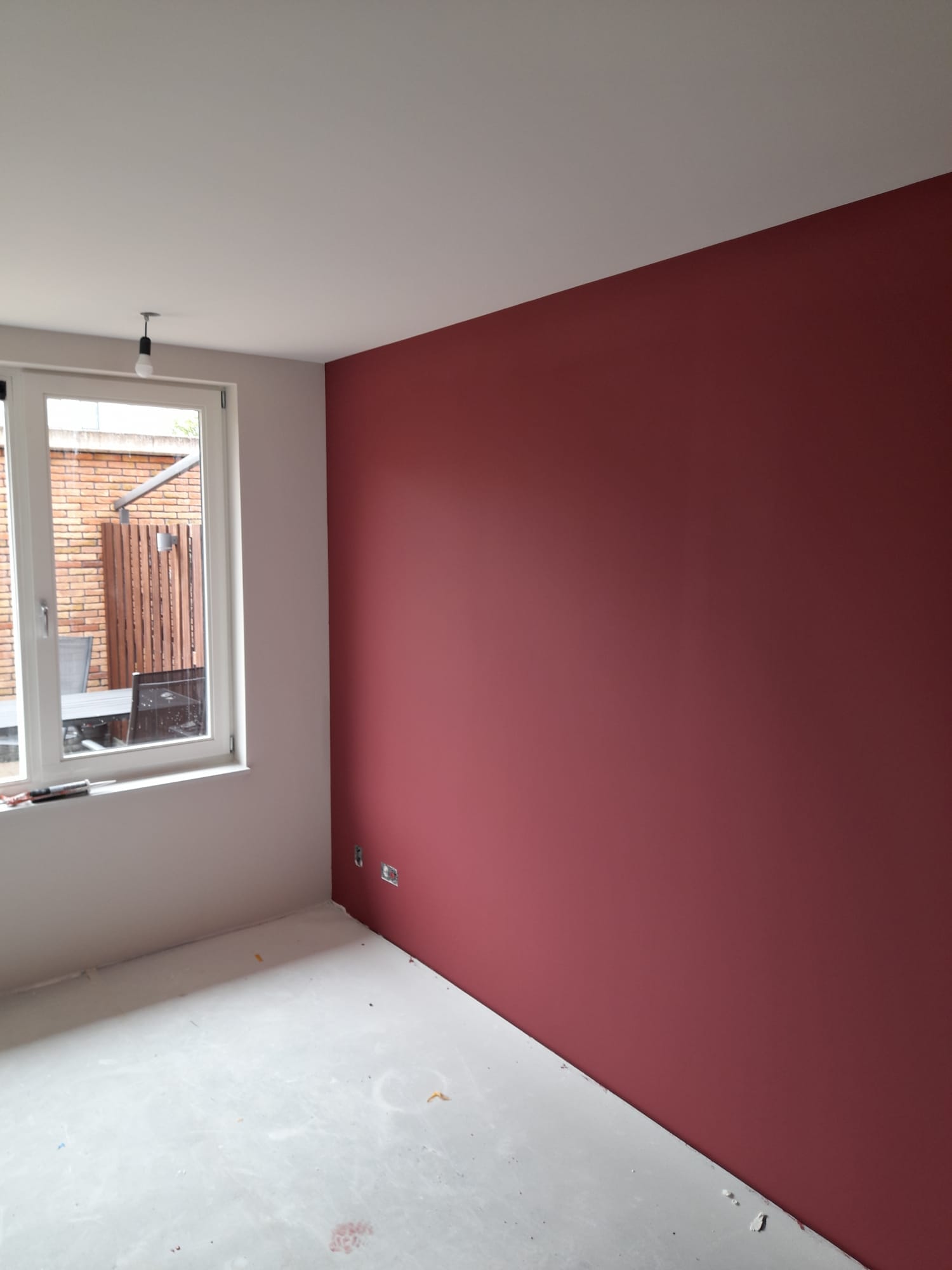 Sauswerk en spuitwerk woning in Lisse 1 Nieuwe kamer met een rode accentmuur, witte muren, een gespoten plafond en een raam met uitzicht op de tuin.