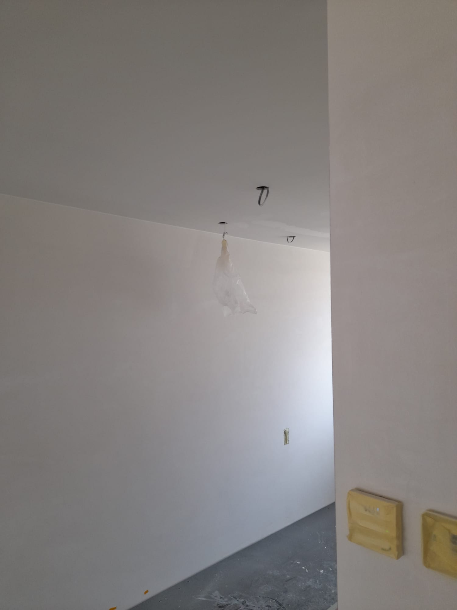 Sauswerk en spuitwerk woning in Lisse 14 Geverfd plafond en wanden van een woning in Lisse. Een lamp is afgedekt met plastic.